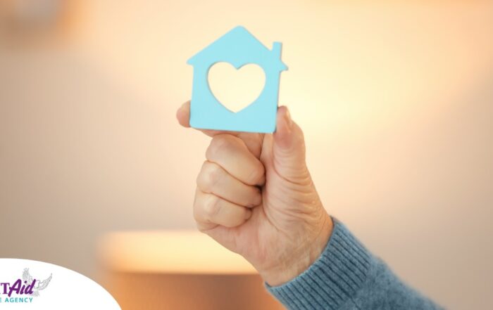A hand holds up a cutout of a home with a heart in it, representing the home care industry.