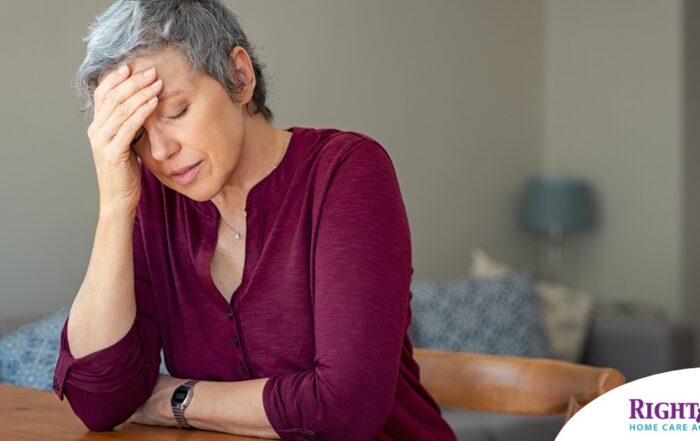 A woman holds her head in her hand, representing the stress that new family caregivers go through.