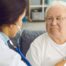 A doctor examines an older man with a stethoscope, representing pneumonia in elderly adults.